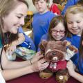 Alex Long (back, left) looks on as (left to right) Maddi Capps, Abby Hood and Addi Capps from Mooreville Elementary School present a bulldog to Mississippi State University College of Veterinary Medicine student Janet Koester. Koester and her classmates tended to injured toys on April 13 at the teddy bear clinic, part of CVM's annual open house celebration. (Photo by MSU College of Veterinary Medicine/Tom Thompson)