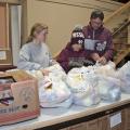 Holiday giving opportunities are an excellent time for parents to model generosity for their children. On Nov. 13, 2014, Mississippi State University student Heather Dodd, left, of Winona, prepares bags of groceries to be distributed to charity along with Latham Blake and his father, John Blake of Starkville. (Photo by MSU Ag Communications/Kat Lawrence)
