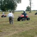 Three young people drive ATVs on a marked course in a field during a safety training.