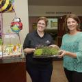 Two women hold a tray of microgreens.