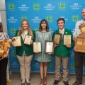 A group of five people, each holding awards, smiling.