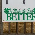 A sign with green text that reads, “To Make the Best BETTER” with 4-leaf clovers on either side.