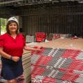 A woman wearing a hard hat standing beside a stack of pallets.