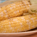 Two ears of seasoned grilled corn on a platter. 