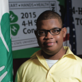 A young boy next to a 4-H flag.