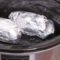 Foil wrapped potatoes in a slow cooker.