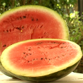 A sliced, ripe watermelon sits on a table outdoors.