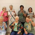 Seven women smile as they hold beaded windchimes.