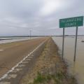 The view down a two-lane road with a wide expanse of water on each side and nearly touching the road. A road sign marks the Tallahatchie County line.