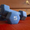 Two blue dumbbells are stacked on a bedroom floor.