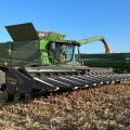 A piece of green farm machinery transfers corn to a bin.