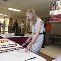 Meaghan Gordon, marketing coordinator at the Mississippi State University Office of Agricultural Communications, cuts the cake May 8, 2014 at the Bost Extension Center that commemorates the 100th anniversary of the Extension Service. Friends of the Extension Service gathered in similar events around the state to celebrate the anniversary. (Photo by MSU Public Affairs/Megan Bean)