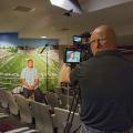 Brian Utley, video producer with MSU Extension’s Agricultural Communications, focuses a camera on former MSU football quarterback Dak Prescott in July 2016. Prescott is the face of the 2017 Public Service Announcement campaign for the 70x2020 Colorectal Cancer Screening Initiative. (Photo by MSU Extension/Kevin Hudson)