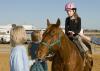 Mary Riley, coordinator for Mississippi State University's 4-H therapeutic riding program, and volunteer Shanna Holder, talk to 9-year-old Elizabeth Howard of Columbus as she sits atop her favorite horse, Bob. Howard's parents, Tommy and Brenda, are donating funds to construct a new therapeutic activity center in West Point. (Photo by Marco Nicovich)