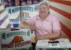 Woman pictured with arms resting on boxes labeled “Mississippi Sweet Potatoes.”