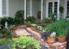 A curving brick walkway lined with plants leads up to a porch.