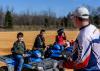 Three young people sit on ATVs as they listen to their instructor.