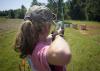 A young person pulls back a bow while aiming at a target.