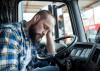 Tired man rests his head in a truck cab.