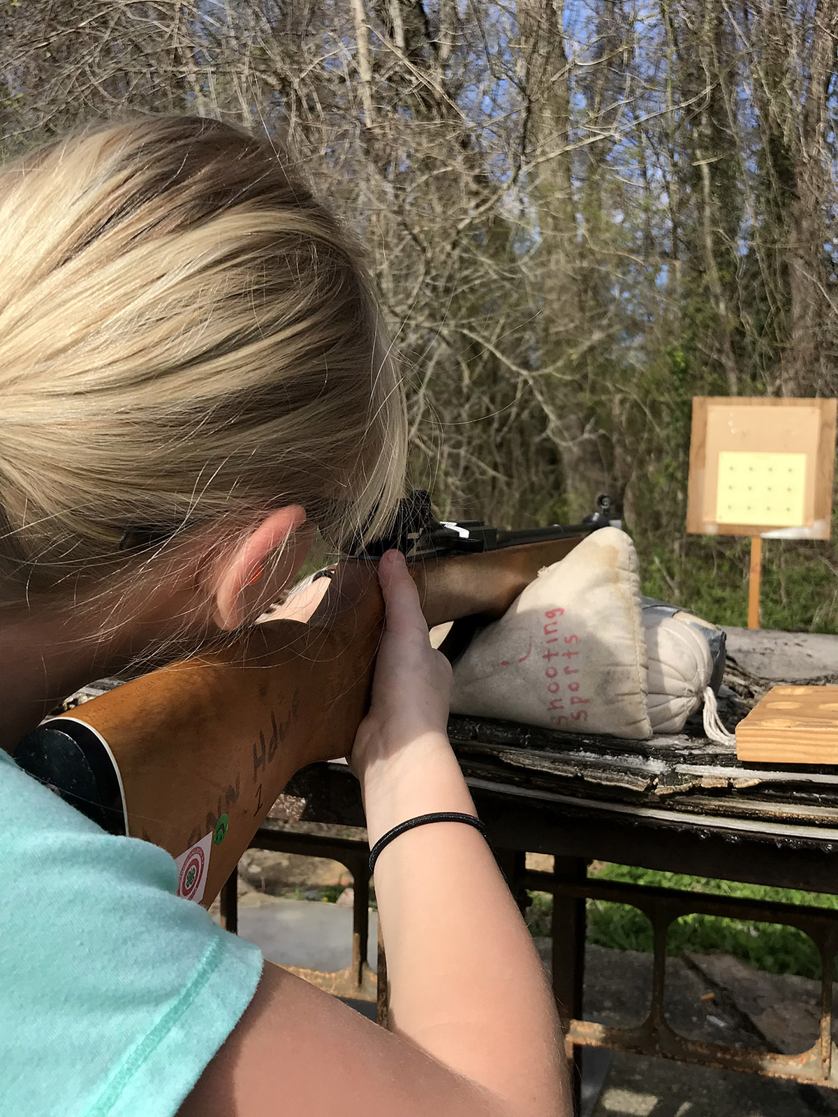 A Shooting Sports participant aims her rifle at a target.