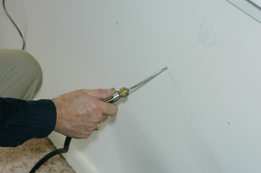 Termiticide foam is being injected into a wall void.  The foam has a consistency similar to shaving cream.