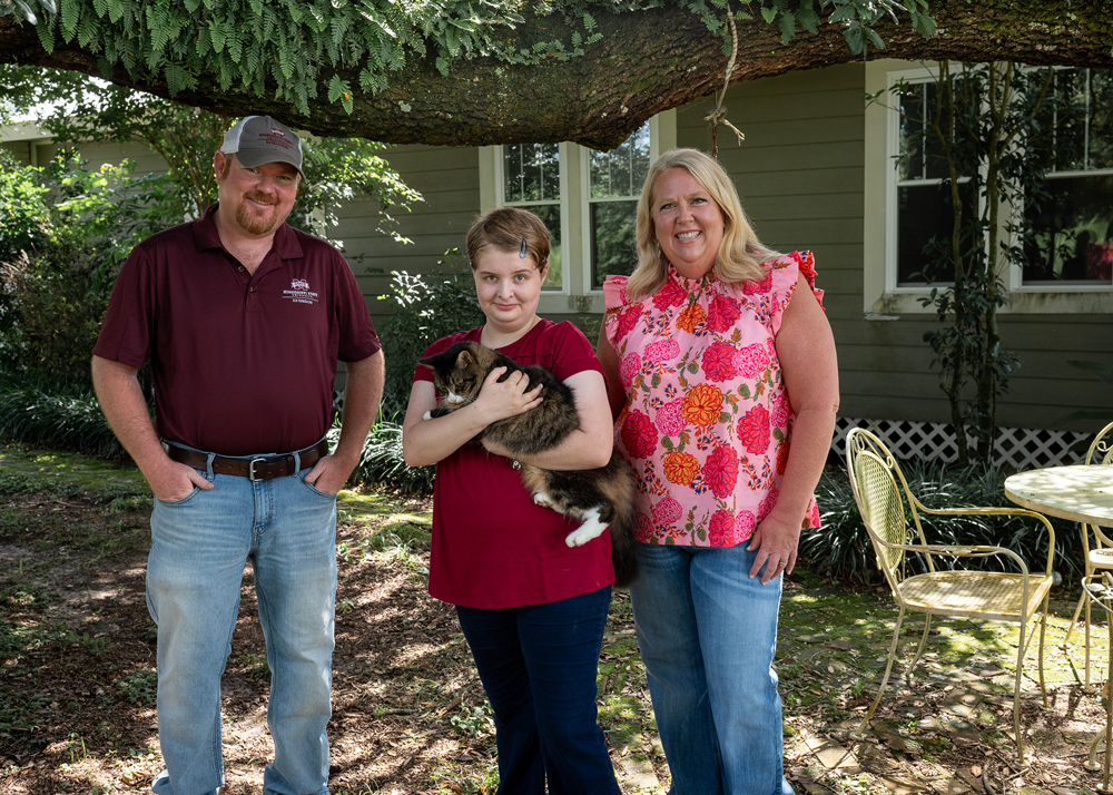 Two adults on either side of a child holding a cat.