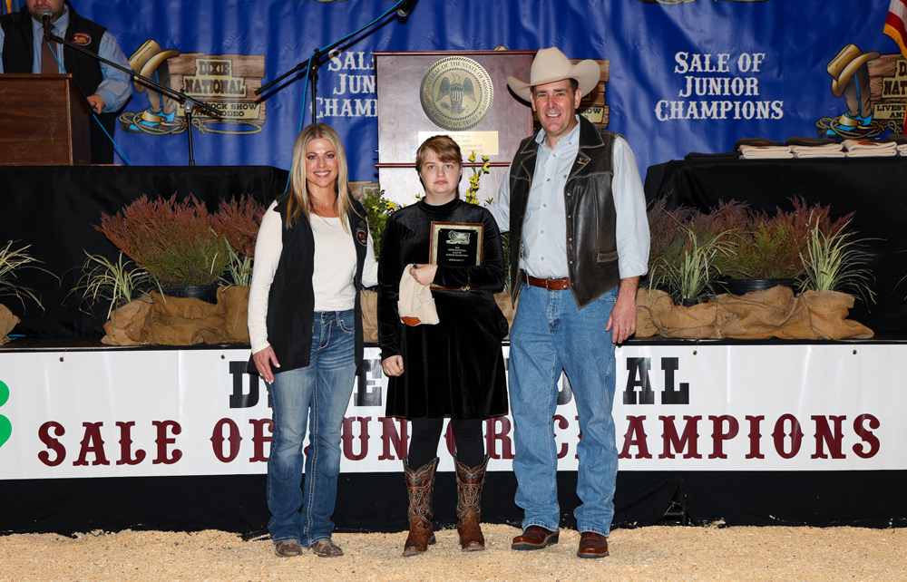 A child holding a plaque with a person on either side of her.