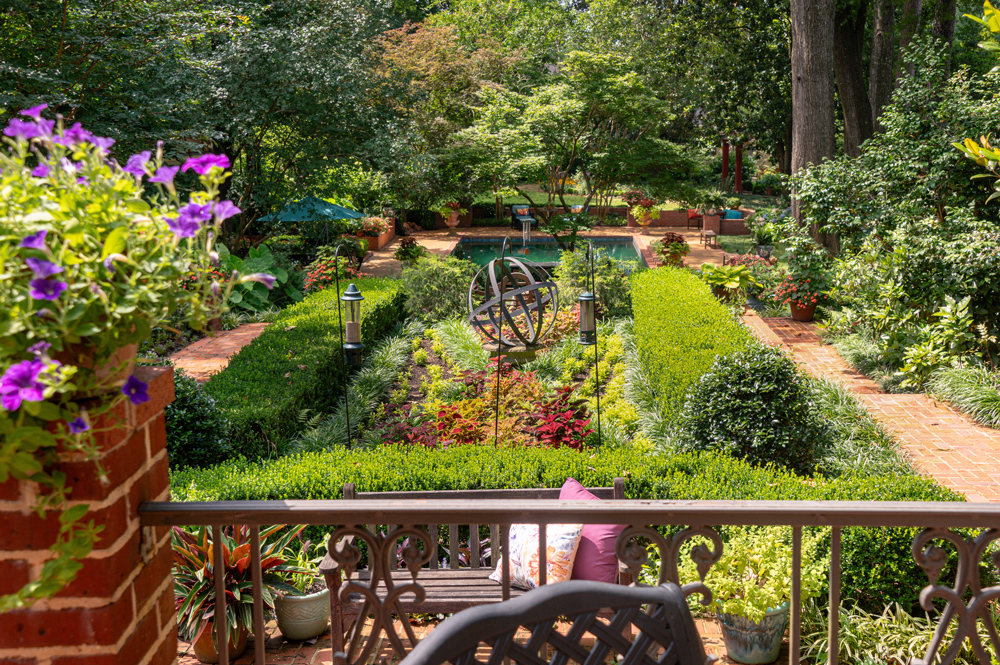 A manicured garden with brick walkways and a small pond.