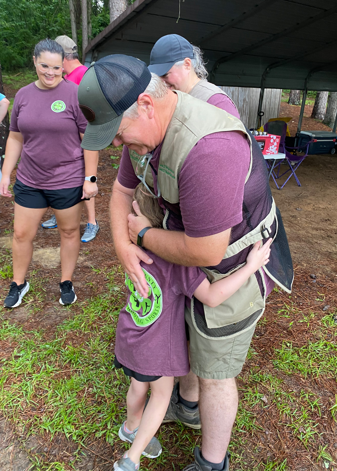 An adult hugging a child outside.
