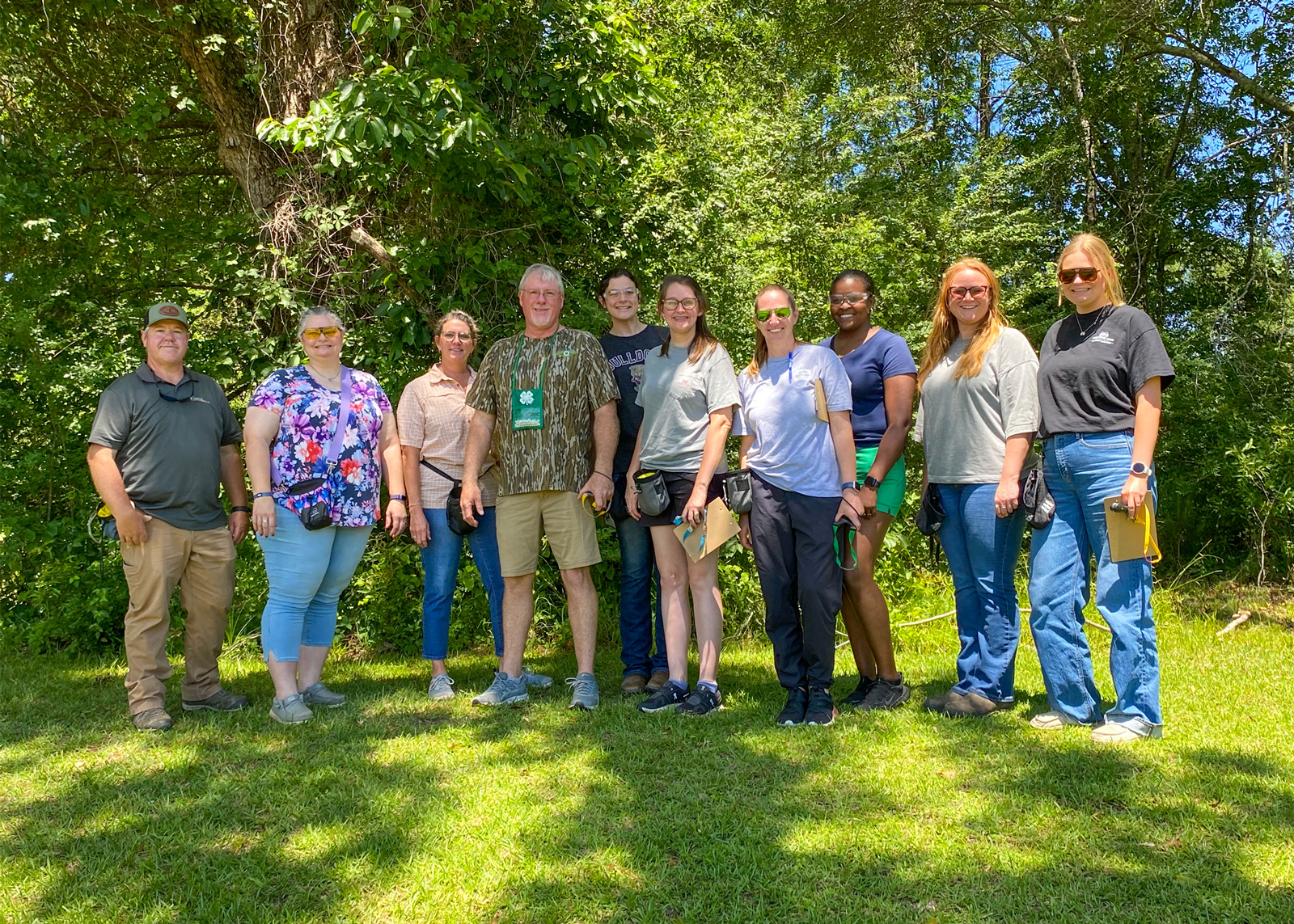 A group of people standing outside smiling.