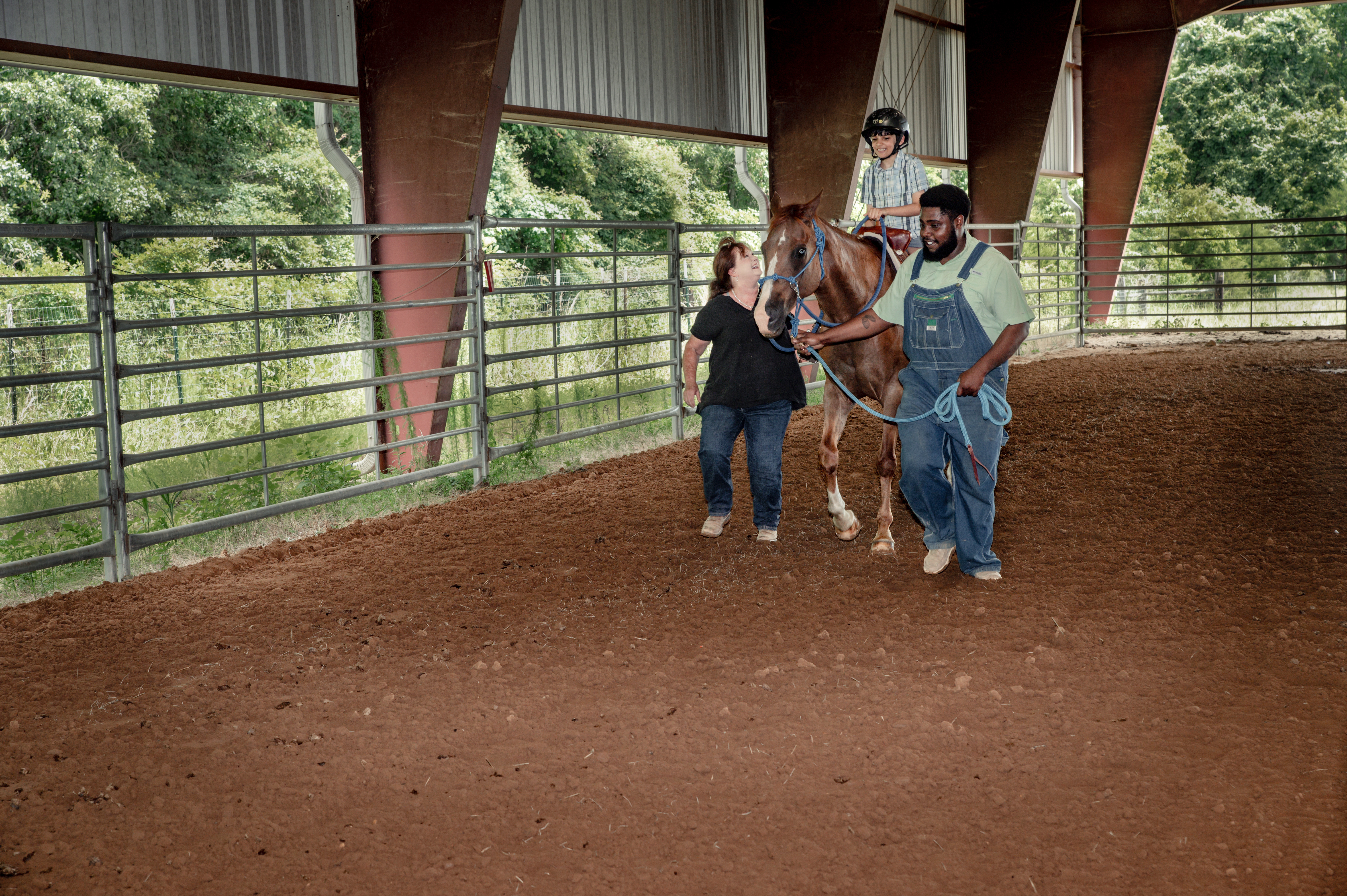 A boy riding a horse, with a man on one side and a woman on the other.