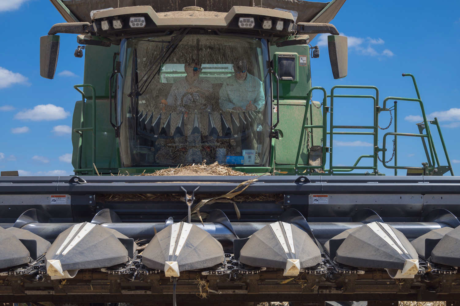 Two men seating in a corn combine.