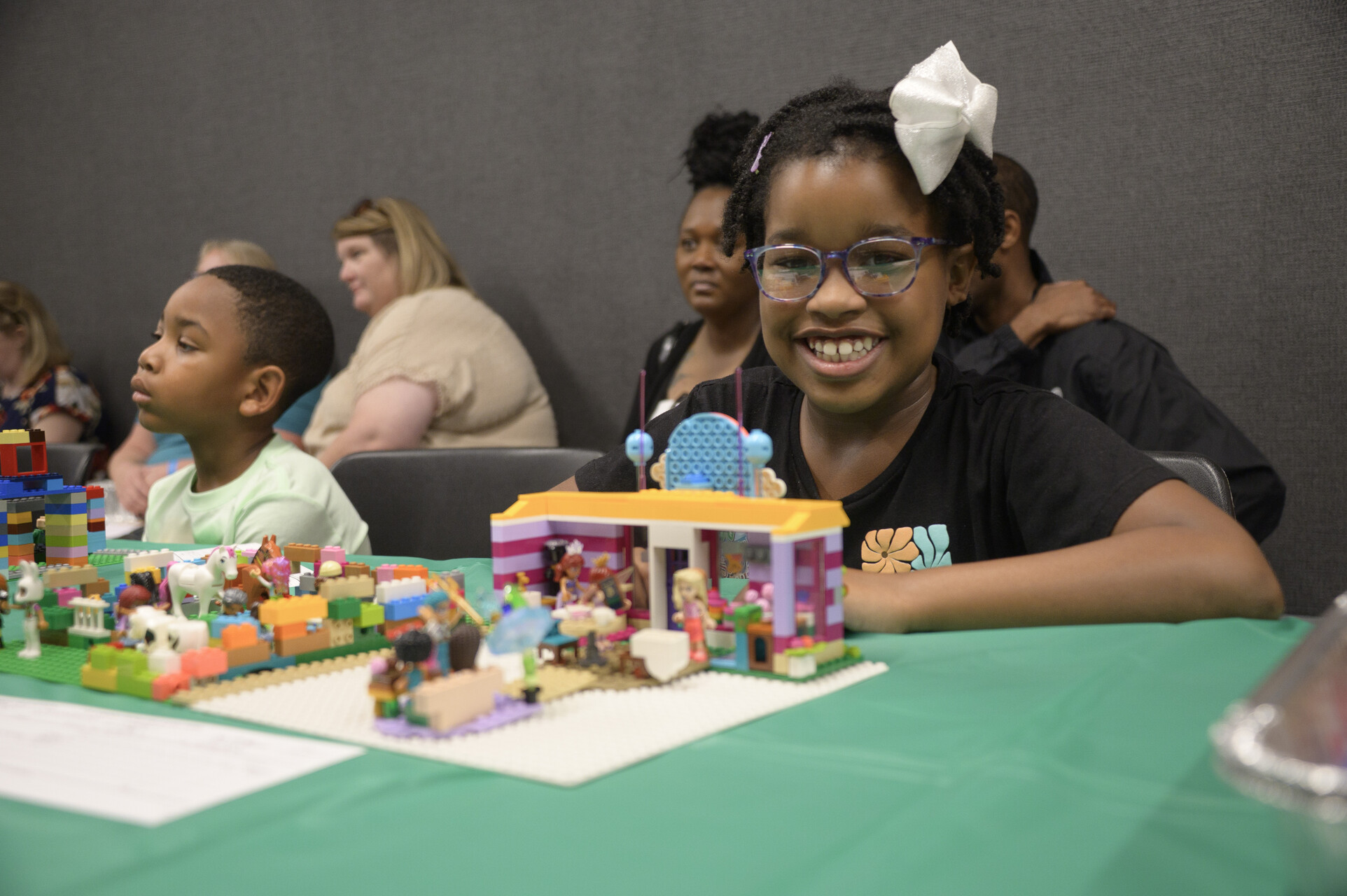 Two young people seated with LEGO creations in front of them.
