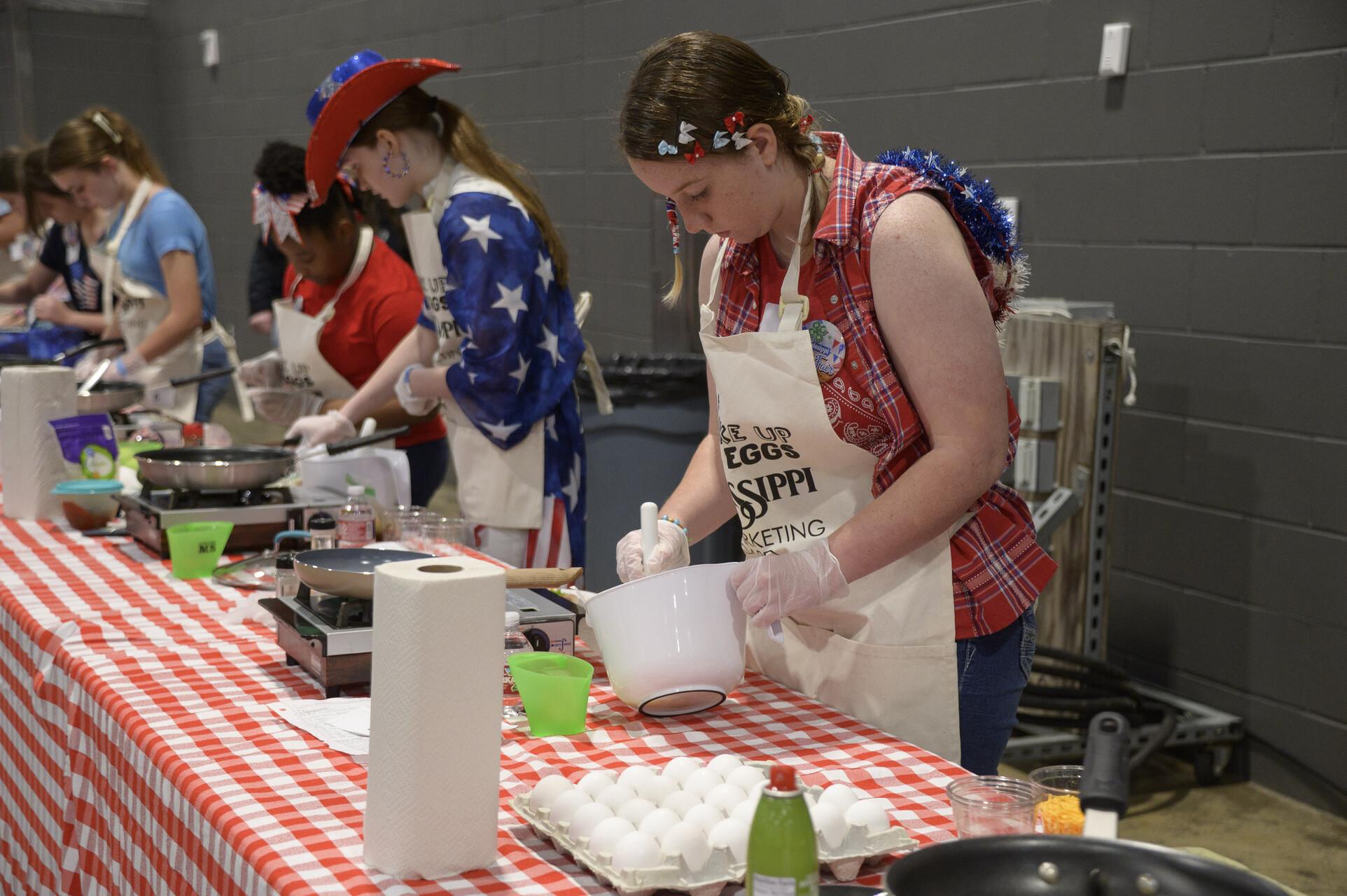 Young people stirring pots at cooking stations.