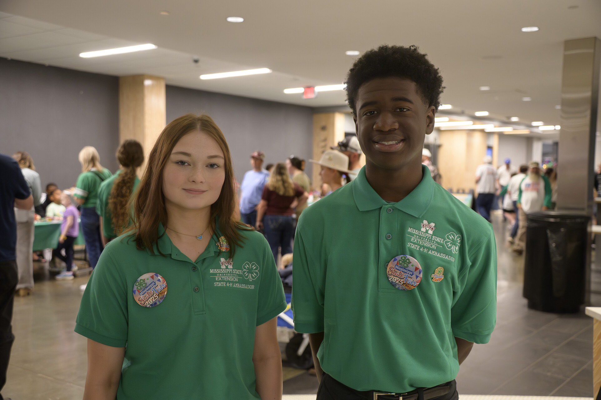 Two young people wearing green polos and smiling.