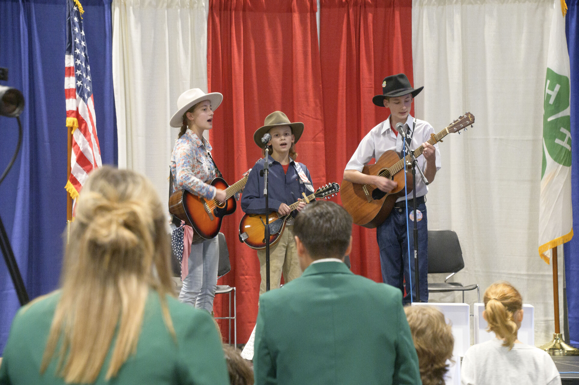 Three young people wearing cowboy hats play guitars.