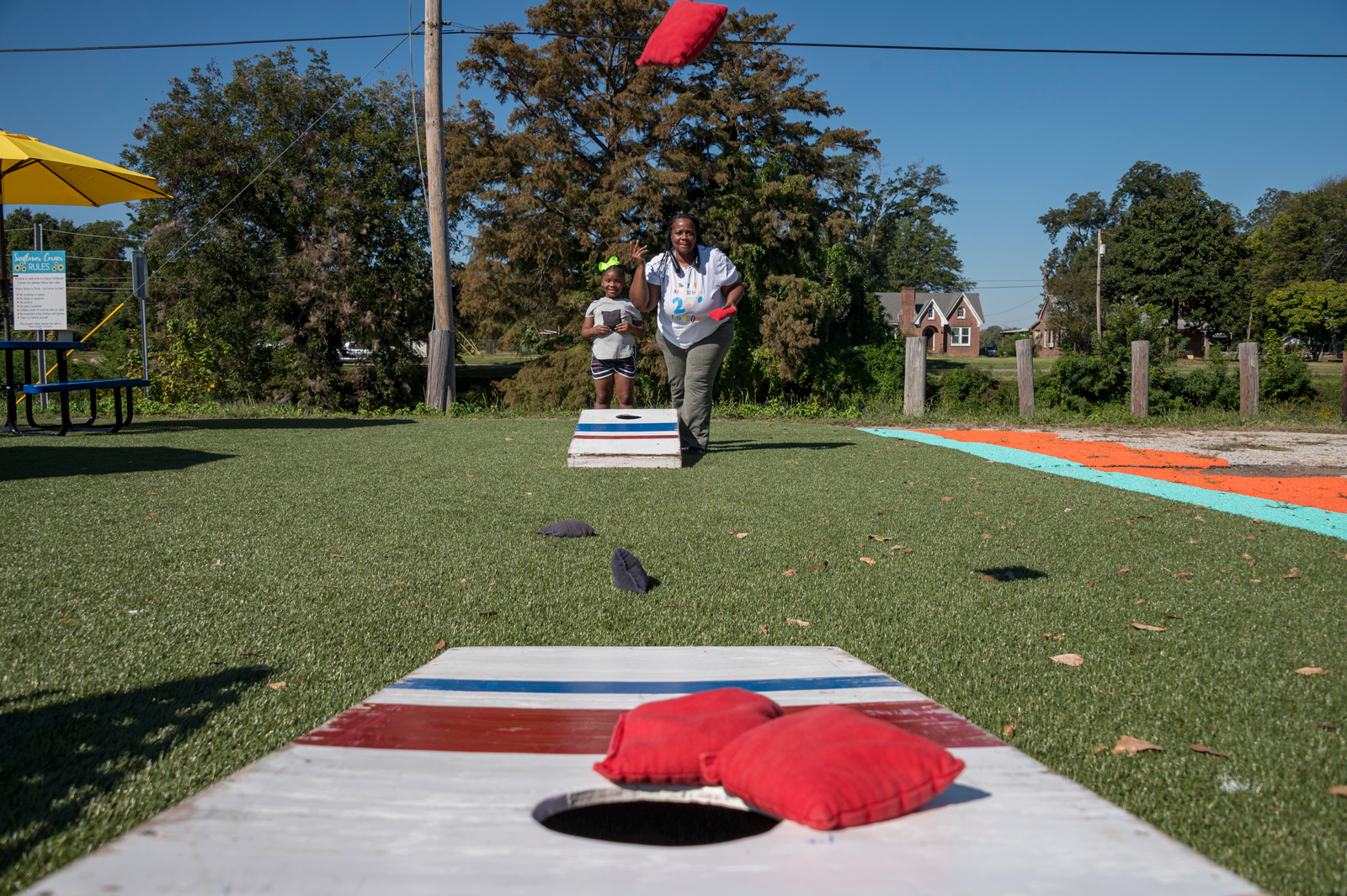 An adult and child playing cornhole.