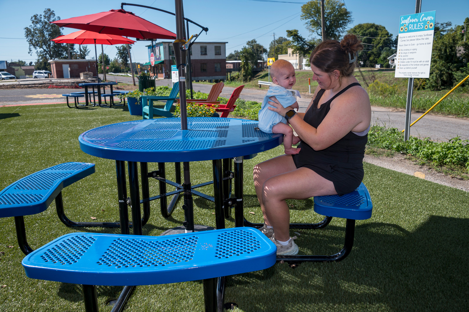 An adult holding baby seated on a picnic table.