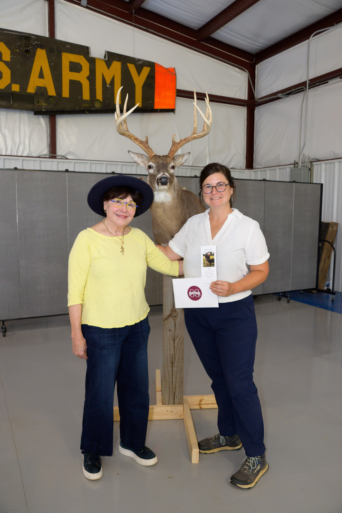 Two people standing in front of a deer mount.
