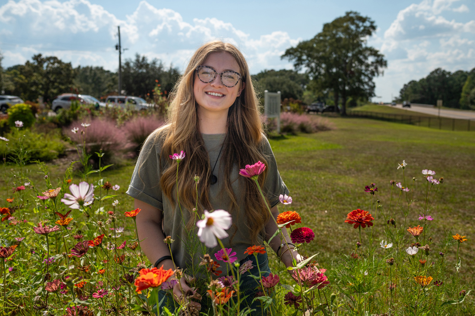 A person standing among zinnias of all colors.