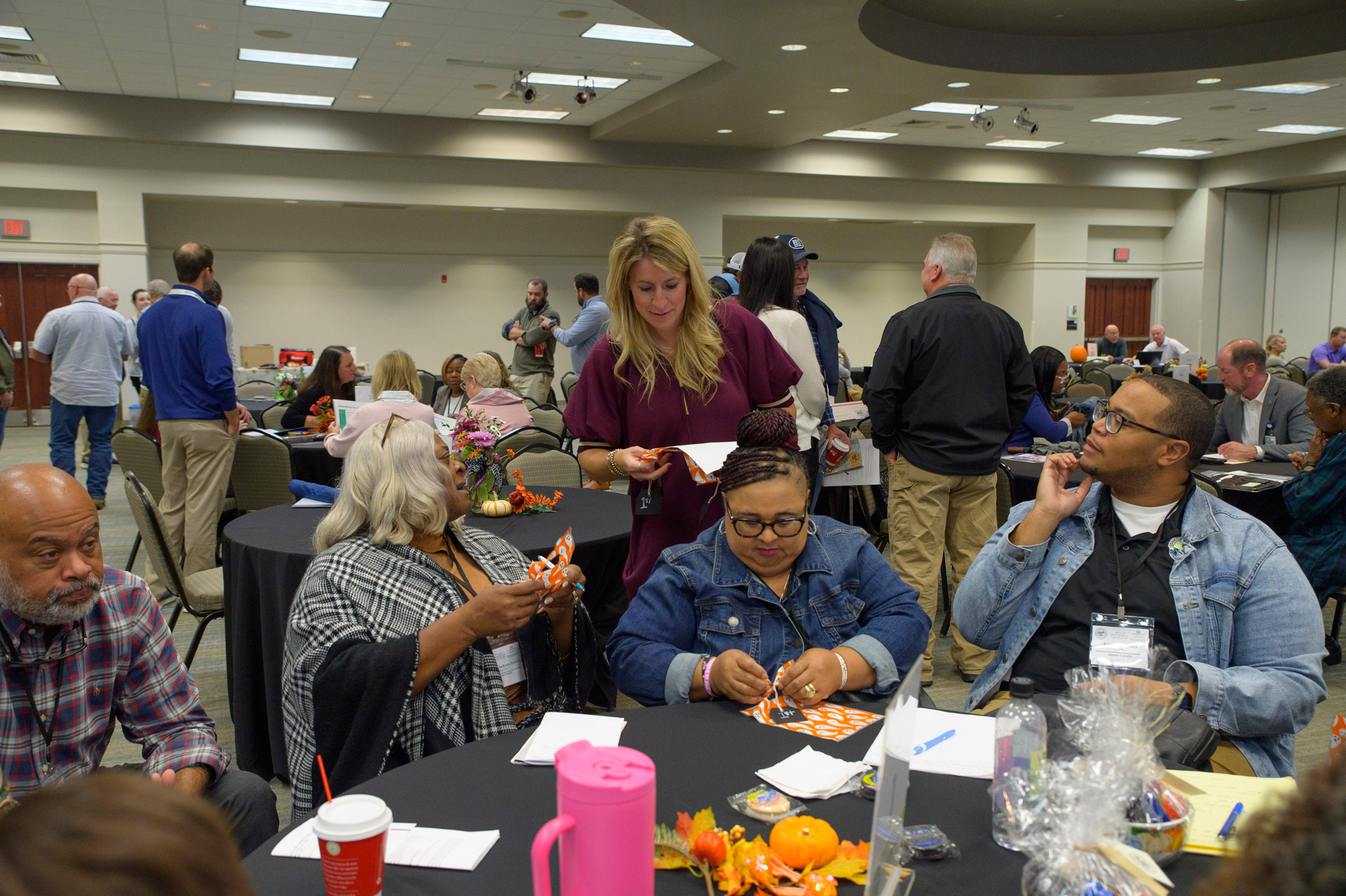 Seated person in a conference room talks to a standing person, as two others watch.