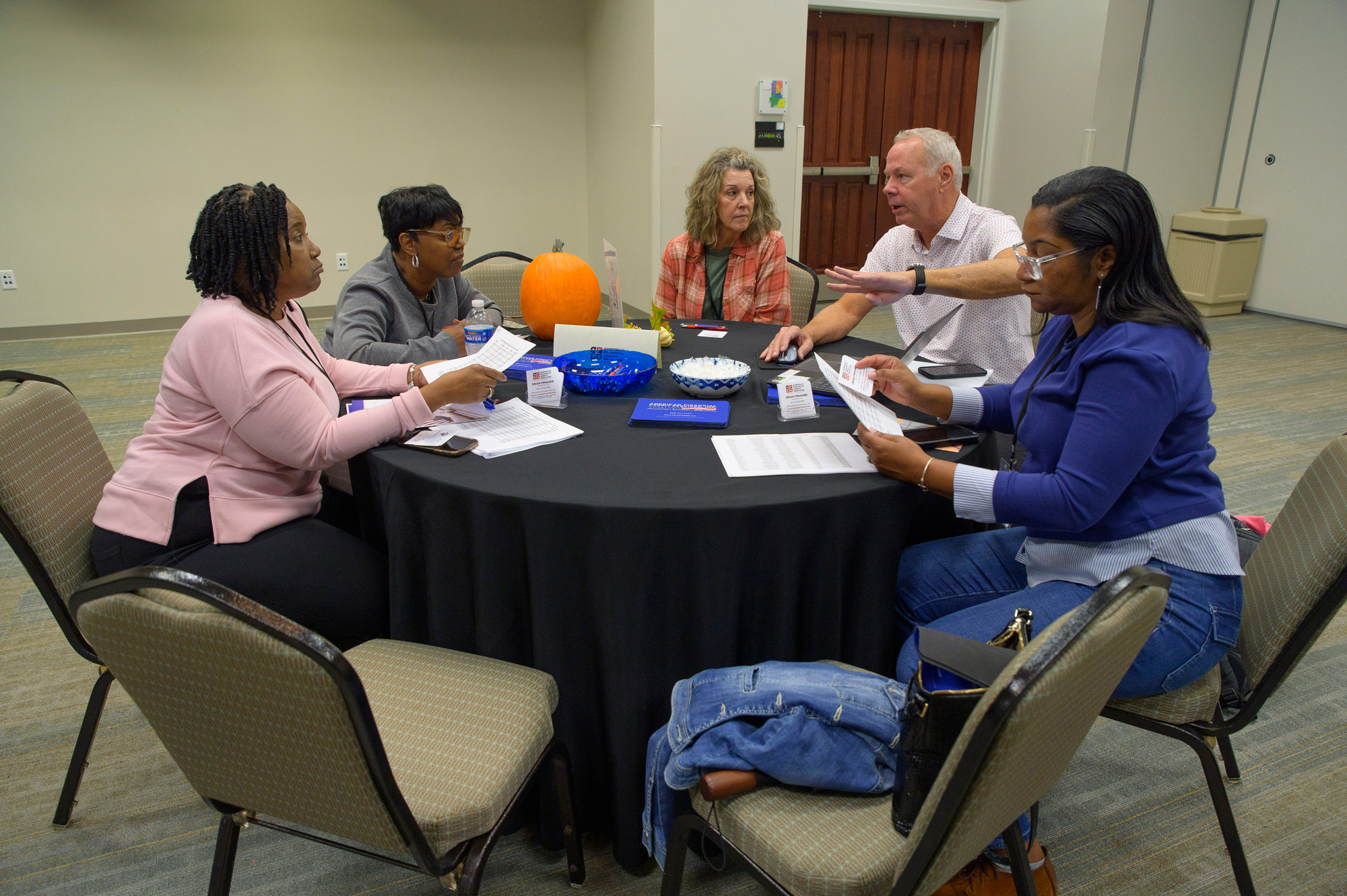 Five people consulting at a table in a conference room.