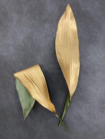 One leaf is spray painted gold while another leaf is folded and partially spray painted.