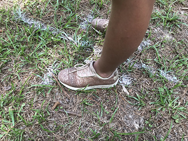 Two feet positioned on opposite sides of a white chalk line on the ground.