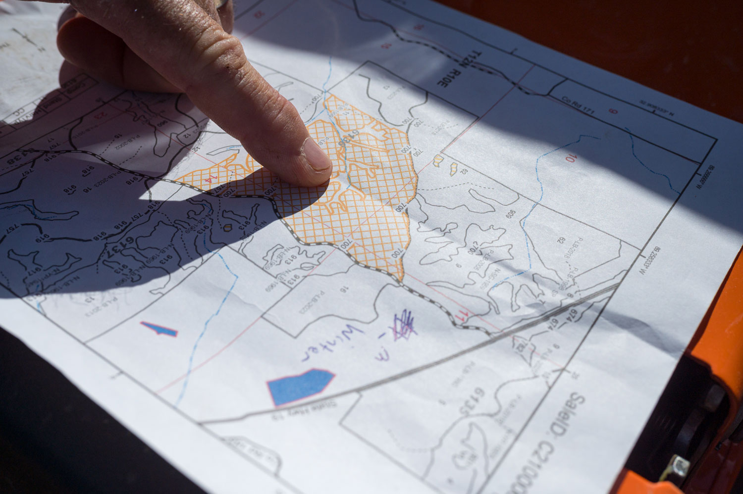 A finger pointing at a location on a printed map.