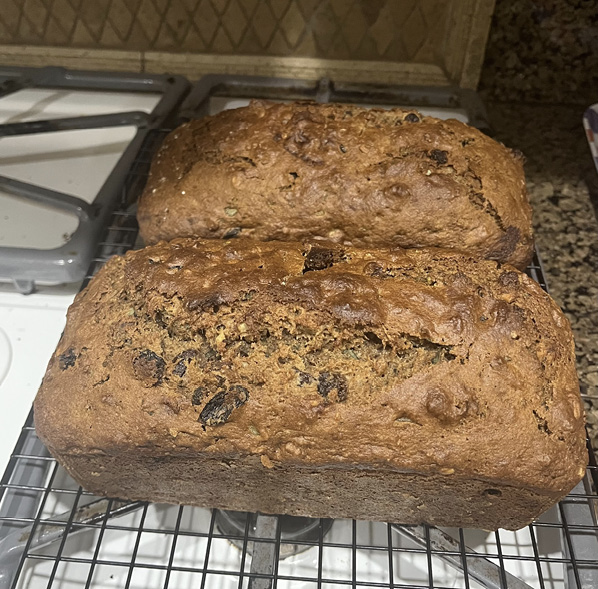 Two loaves of purslane walnut bread sit on a baking rack.