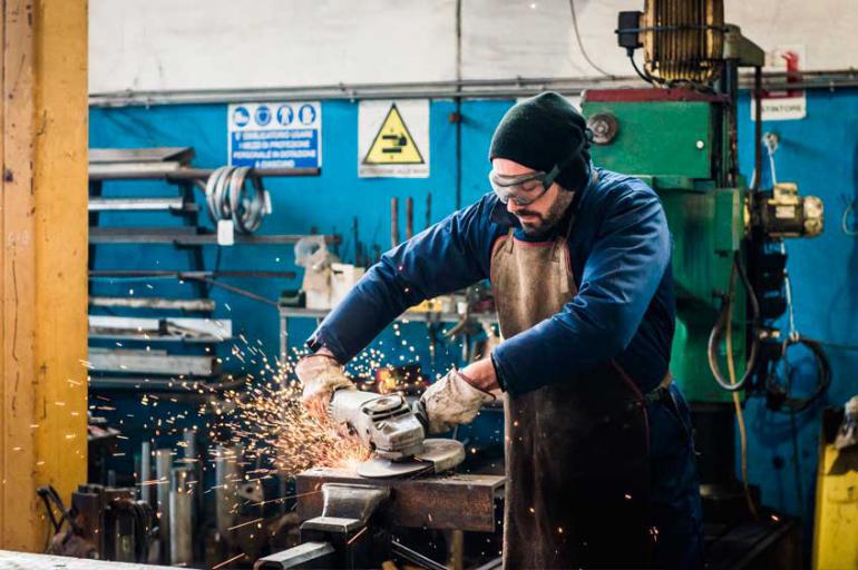 A man with a beanie and protective glasses working in a shop