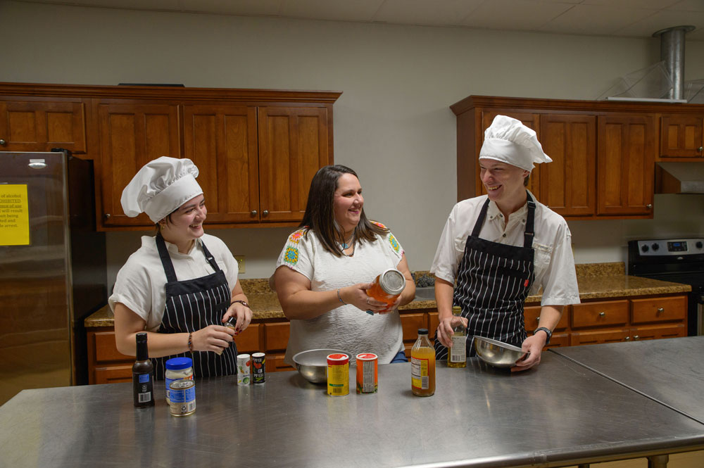 Two young people and an adult look at a jar of honey.