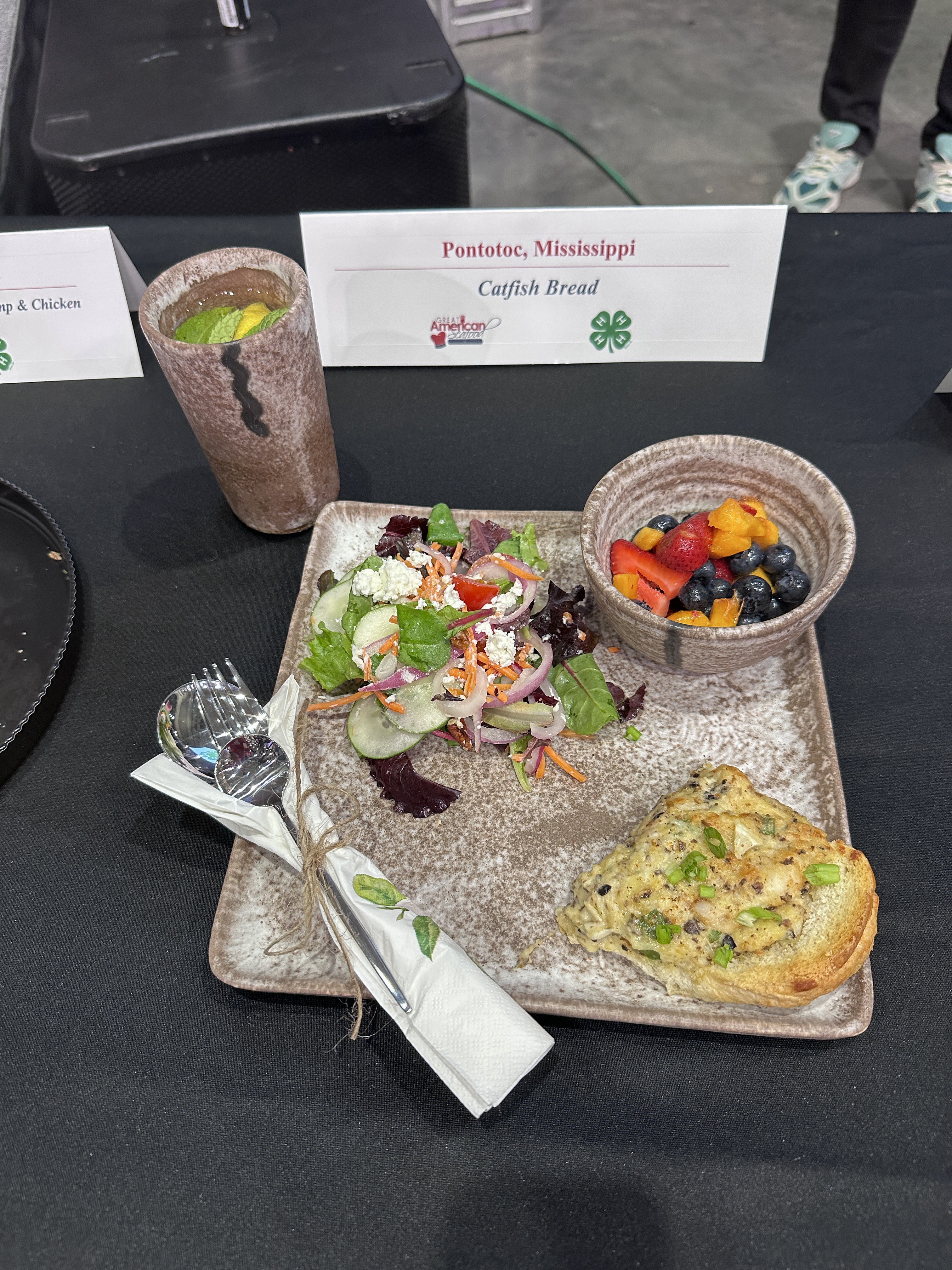 A plate of food, with a bowl on it and a drink beside it.