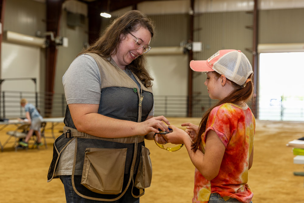 A person hands a child safety glasses.